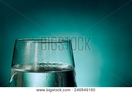Glass Of Fresh Water Covered In Water Droplets Isolated In An Aqua Colored Background