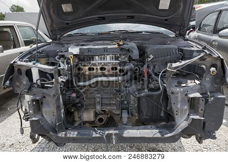 The Engine Compartment Of A Wrecked Car Reveals Missing Parts, Inlcuding The Bumper, The Radiator An