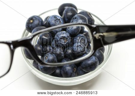 Bilberry Cure For Eyes Concept With Glasses. Glasses Linse Magnifying The Blueberries.