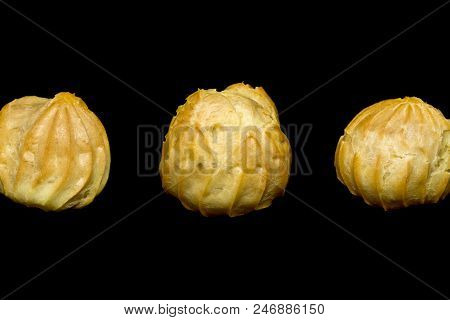 Row Of Three Profiteroles Isolated On The Black Background.