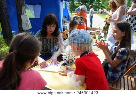 Russia, Koltsovo - June 23, 2018: Female teacher giving master class at open air art studio during celebrating the International Festival of National Cultures in small science city Koltsovo in Siberia