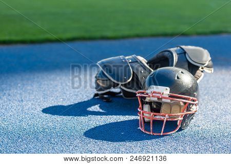 American Football Helmet With Chest Protection Lying On Blue Rubbery Surface At Stadium