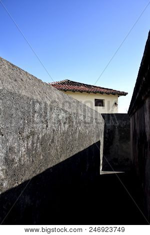Perspective View Of Pathway Among Gray Textured Wall Of Matachin Fort On Coast Of Baracoa City, Cuba