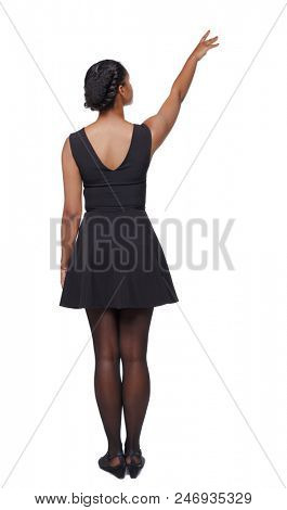 back view of a black African-American woman in a brown dress pointing upwards. Rear view people collection.  backside view of person.  Isolated over white background. The girl saw something in the sky