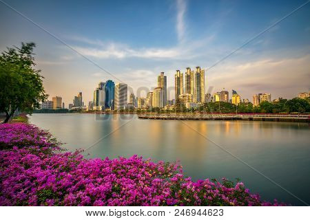 Lake Ratchada Situated In The Benjakitti Park With Beautiful Flowers In The Foreground And Modern Hi