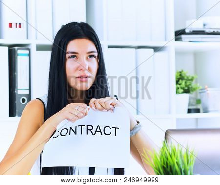 Young Angry Female Office Worker Ripping Contract At The Desk.