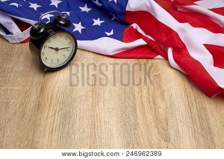National flag of America and black alarm clock on old wooden background