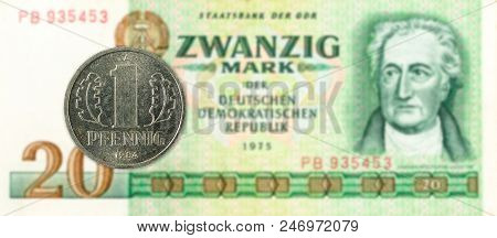 1 Pfennig Coin Against Historic 20 East German Mark Bank Note