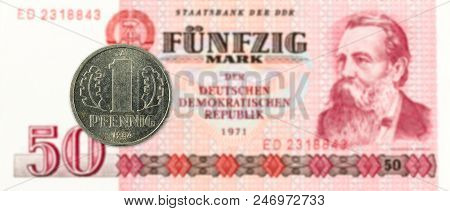 1 Pfennig Coin Against Historic 50 East German Mark Bank Note