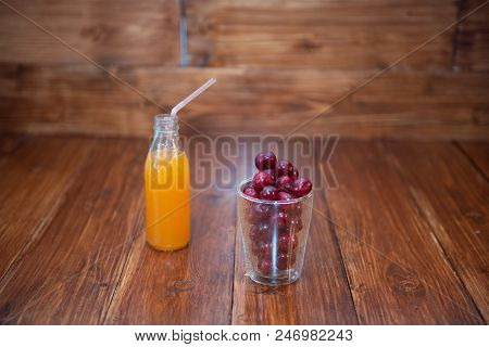 Sweet Cherry, Black Cherries In A Glass On Wooden Background With Fresh Juicy In Glass Bottle.