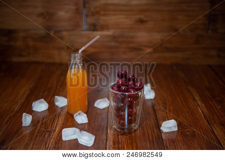 Sweet Cherry, Black Cherries In A Glass On Wooden Background With Fresh Juicy In Glass Bottle. Ice A