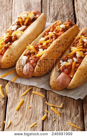 Delicious Chili Hot Dogs With Cheddar Cheese, Spicy Beef Mince, Onion And Sauce Close-up. Vertical,