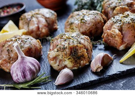 Raw Rabbit Ballotine Prepared To Be Cooked On A Black Slate Plate With Herbs And Spices, Horizontal 