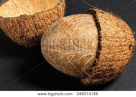Chopped Coconut In Two Halves With A Whole Inner Soft Nut Lie On A Black Stone