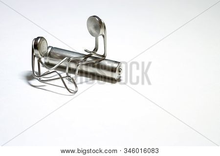 Two Little Men Are Made Of Paper Clips. One Man Is Sitting On A Cylindrical Battery, The Other Is Ne