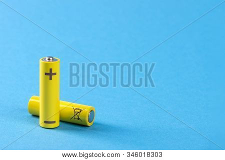 Two Yellow Batteries On A Blue Background With Place For Text