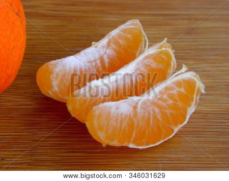 Three Slices Of Mandarin On Wooden Background