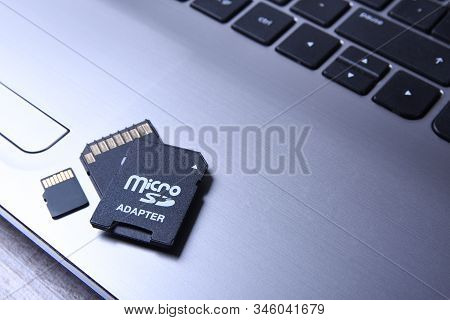 Micro Sd Memory Card Adapter On Grey Laptop Keyboard On The Wooden Table. Close Up