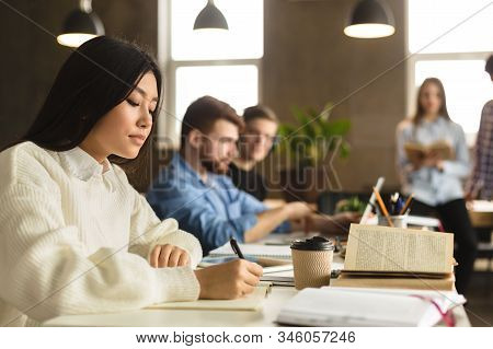 Exam Preparation. Girl Noticing Material To Copybook, Taking Notes In College Library