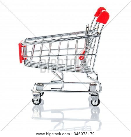 Side View Of Empty Chromed Toy Market Shopping Cart With Red Handle And Plastic Board On The Front. 