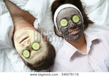Top-view Of Man And Woman Making Spa Procedures Applying Wetting Facial Masks And Fresh Cucumber On 