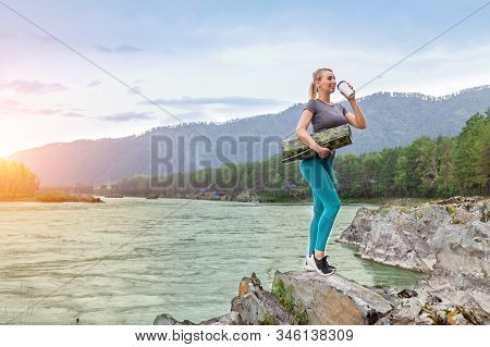 Blond Beautiful Strong Girl Standing On The Stone Cliff Ground Resting After Sport Outdoors Drink Te