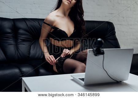 Cropped View Of Sexy Woman In Skirt And Bra Taking Off Stockings In Front On Laptop With Web Camera