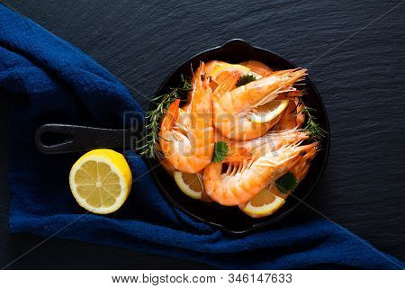 Seafood Concept Ocean King Prawns Cooked In Skillet Iron Cast On Black Slate Stone With Blue Napkins