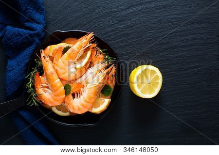 Seafood Concept Ocean King Prawns Cooked In Skillet Iron Cast On Black Slate Stone With Blue Napkins