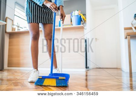 Afro Woman Sweeping Floor With Broom At Home.