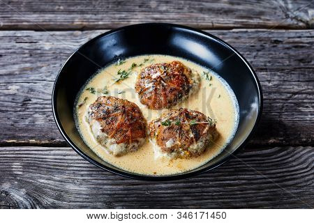Rabbit Ballotine In A Creamy Mustard Sauce With Herbs And Spices In A Black Bowl On A Rustic Wooden 