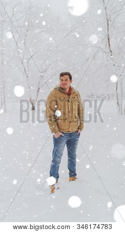 Portrait Of Young Man In Jacket And Jeans In Winter Season. Handsome Man Stands And Squint In Winter