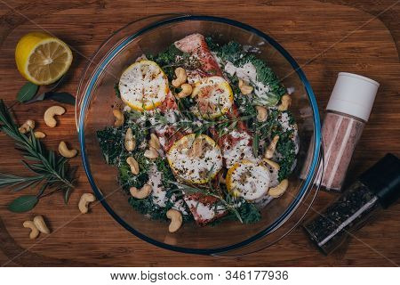 Flat Lay Photo Of Ready To Go To Oven Fish In Glass Pot With Lemon Salt Pepper Rosemary And Cashew N