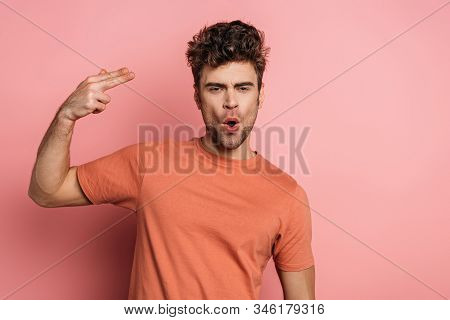 Young Man Imitating Self-killing By Shooting On Pink Background
