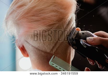 Hairdresser Machine Cuts Woman Client. A Short Haircut, Shaved Temple And A Drawing On The Hair.