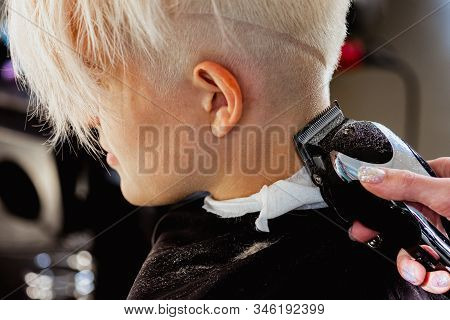 Hairdresser Machine Cuts Woman Client. A Short Haircut, Shaved Temple And A Drawing On The Hair.