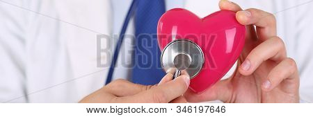 Male Medicine Doctor Holding Red Heart And Putting Stethoscope Head Close To It Closeup. Medical Hel