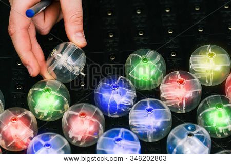 A Mans Hand Inserts A Round Lamp Into An Electrical Network. Colored Light Bulbs. Led Lamp