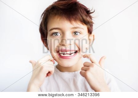 Horizontal Portrait Of 7 Years Old Smiling Child In White T-shirt Flossing His Teeth On White Backgr