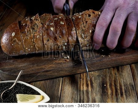 Closeup View Of Chef Slicing Bread On Wooden Cutting Board. Cutting A Bread.