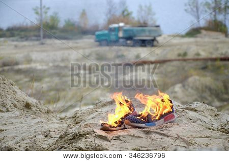 Burning Sports Sneakers Or Gym Shoes On Fire Stand On Sandy Beach Coast. Athlete Burned Out. Physica