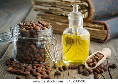 Pine Nuts And Pine Nuts Essential Oil Bottle On Wooden Table.