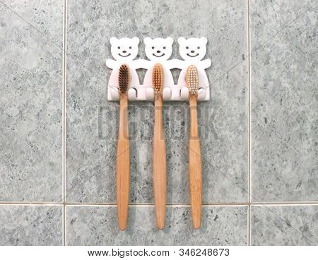 A Family Set Of Three Bamboo Toothbrushes Hang On The Bathrooms Wall In Toothbrush Holder. Ecologica