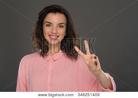 Portrait Of A Young Woman Of 30-35 Years Of Model Appearance, Showing Her 2 Fingers On Her Hand.