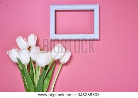 Light Wooden Frame With Many White Tulips Are On The Pink Background. Top View, Copy Space