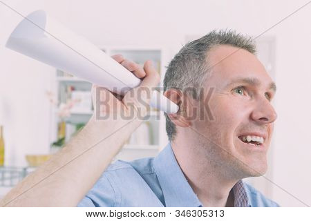 Man wearing deaf aid in ear attempting to hear something