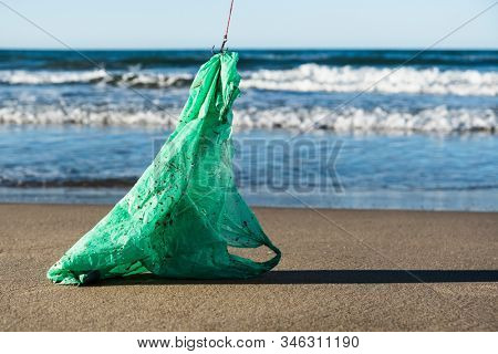 closeup of a used green plastic bag in a fish hook, freshly fished in the ocean