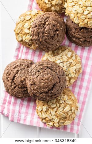 Cereal oatmeal and chocolate cookies on checkered napkin.