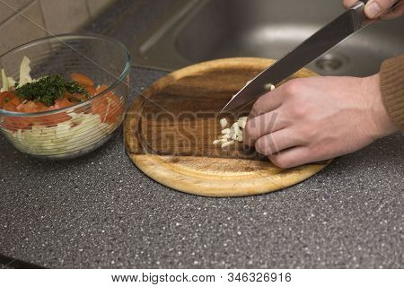 Man Cutting Garlic With A Knife. Vegetable Prepring In The Kitchen Bord. Healhy Chopping Ingreient F