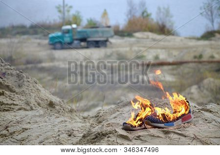 Burning Sports Sneakers Or Gym Shoes On Fire Stand On Sandy Beach Coast. Athlete Burned Out. Physica